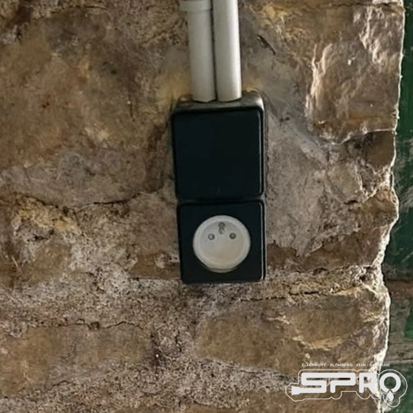 Il s'agit de deux boitiers prise noires et blanc raccordés sur un mur en pierre d'extérieur.