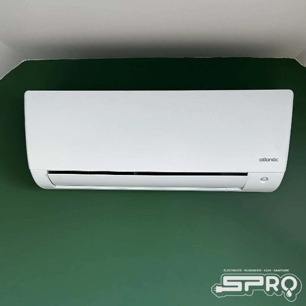 Bloc de climatisation posé sur un mur vert.