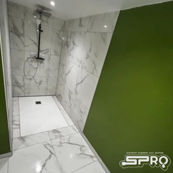 Douche avec un carrelage imitation marbre, le mur dessous est de couleur verte. La tuyauterie est argenté.